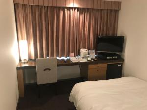 um quarto de hotel com uma secretária com um computador e uma cama em Twin Leaves Hotel Izumo em Izumo
