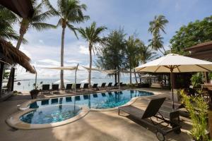 Laem Sor的住宿－三曼塔瑞特酒店，毗邻大海的带椅子和遮阳伞的游泳池