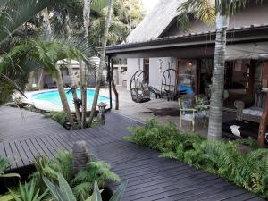 a house with a wooden deck next to a swimming pool at Lodge Afrique in St Lucia