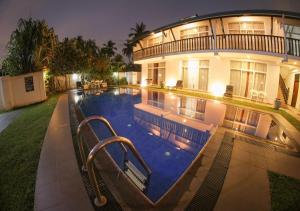 uma casa grande com uma piscina em frente em White Rose Beach Resort em Marawila