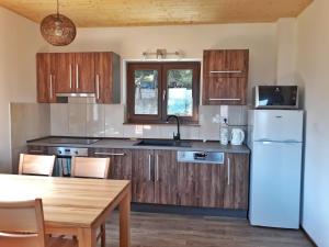 a kitchen with wooden cabinets and a white refrigerator at Chata OSTRUZINA 9 in Lipno nad Vltavou