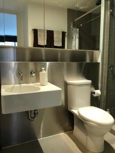 a bathroom with a white toilet and a sink at Chic Fitzroy Street Apartment in Melbourne