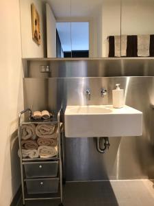 a bathroom with a sink and a towel rack at Chic Fitzroy Street Apartment in Melbourne