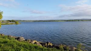a large body of water with rocks in the foreground at Lakeside Loughrea in Loughrea