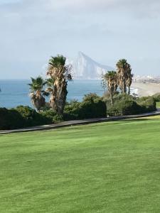 um parque com palmeiras e vista para o oceano em Alcaidesa Golf & Relax em La Alcaidesa