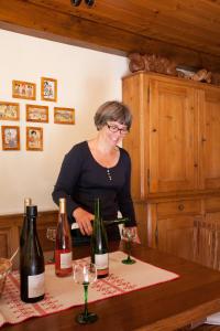 une femme debout à une table avec deux bouteilles de vin dans l'établissement Gîtes Le Tokay et Le Muscat, à Gertwiller