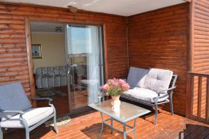 a patio with two chairs and a table with flowers on it at Alto Log Cabin in Madeteleli