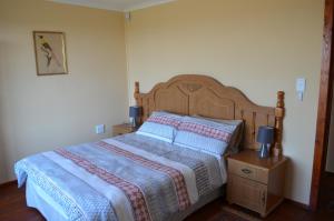 Schlafzimmer mit einem großen Bett mit einem Kopfteil aus Holz in der Unterkunft Alto Log Cabin in Madeteleli