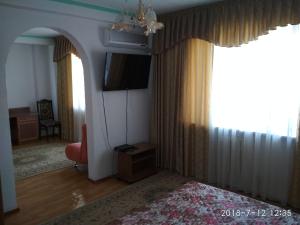 una sala de estar con TV y una habitación con cama en Green Hotel, en Almaty