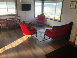 a living room with two red chairs and a table at Waratah Falls Holiday Unit in Waratah
