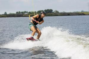 a man riding a wave on a surfboard in the water at Camping Marina Eemhof in Zeewolde