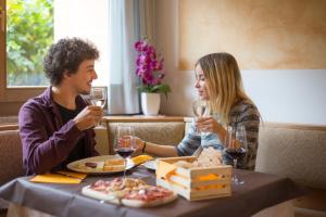 a man and woman sitting at a table with wine glasses at Hotel Angelo in Andalo