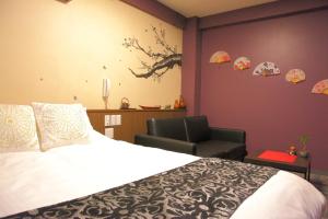 a bedroom with a bed and a chair and umbrellas on the wall at Hotel Neo World in Osaka