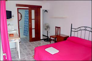 コニル・デ・ラ・フロンテーラにあるHabitación Velardeのピンクベッド1台、デスク、椅子が備わるベッドルーム1室が備わります。