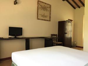 a room with a bed and a desk with a television at Casale Ai Poggi in Orbetello