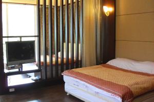 a bedroom with a bed and a tv and a window at Maylin B&B in Xinshe