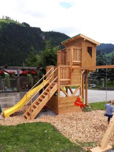 eine Holzspielstruktur mit einer Rutsche und einem Spielplatz in der Unterkunft Appartements Stockinger in Großarl