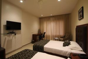 a hotel room with two beds and a flat screen tv at Hotel Hyderabad Grand in Shamshabad