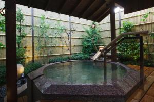 una bañera de hidromasaje en un jardín con una fuente en Kizukuri no Yado Hashizuya en Misasa