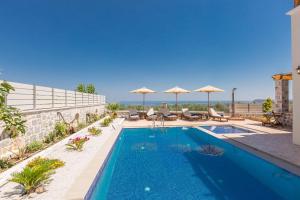 a swimming pool with chairs and umbrellas on a building at New Villa Katifes with Pool, Walk to Amenities & Amazing Views! in Kiriánna