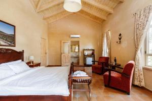 a bedroom with a bed and a couch and chairs at Smadar-Inn in Zikhron Ya‘aqov