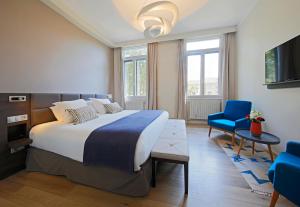 ein Schlafzimmer mit einem großen Bett und einem blauen Stuhl in der Unterkunft Negrecoste Hôtel & Spa in Aix-en-Provence
