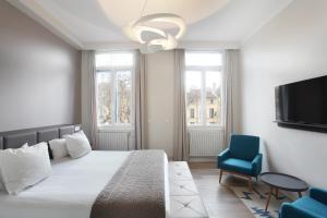 a bedroom with a bed and a blue chair at Negrecoste Hôtel & Spa in Aix-en-Provence +92 photos