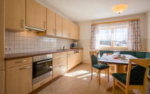 a kitchen with wooden cabinets and a table with chairs at Village Apartments in Achenkirch