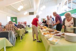 un grupo de personas de pie alrededor de las mesas con comida en Hotel Nordborg Sø, en Nordborg