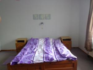 a bed with a purple comforter in a room at Luca-lak in Fonyód