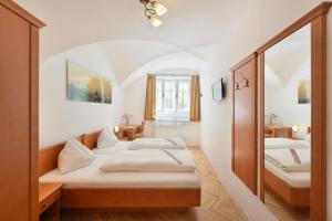 a bedroom with two beds and a mirror at Hotel Krone 1512 in Salzburg