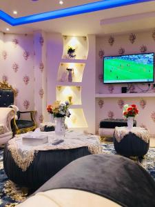 a living room with a tv and a table with flowers at Bahget Eljouf Furnished Apartment in Aţ Ţuwayr