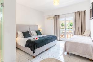 a white bedroom with a bed and a window at Vergina Studios & Apartments in Malia