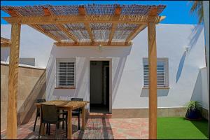 a wooden pergola with a table and chairs on a patio at Bungalow La Roa IV in Conil de la Frontera