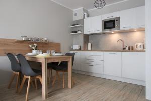 コウォブジェクにあるCHILLIapartamenty - Bliżej Morza - SMILEの白いキャビネット、木製テーブルと椅子付きのキッチンが備わります。