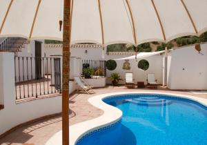 a pool with an umbrella next to a house at Valle de Oro in Villanueva de Algaidas