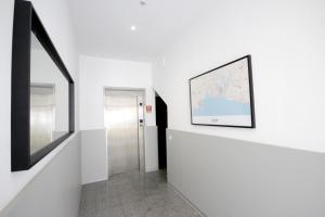 a hallway with white walls and a framed map on the wall at Hospedaria Buganvilia Alvor in Alvor