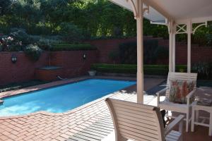 a swimming pool with two chairs and an umbrella at Southey House in Kloof