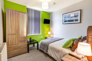 a bedroom with green walls and a bed at Clen Holme House in Crewe