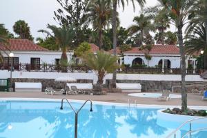 - une piscine en face d'un complexe avec des palmiers dans l'établissement Maspalomas Experience Holiday House, à Maspalomas