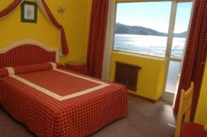 a bedroom with a red bed and a large window at Las Islas in Vilaboa