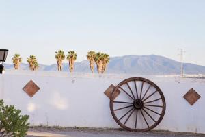 a wall with a wooden wheel on the side of it at Hotel Cortijo del Arte - Caminito del Rey in Pizarra +80 photos