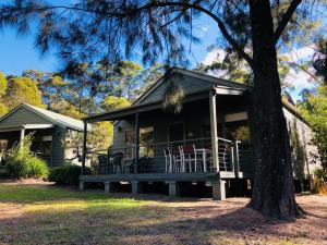 una casa con un porche con sillas. en Kangaroo Valley Golf and Country Retreat en Kangaroo Valley