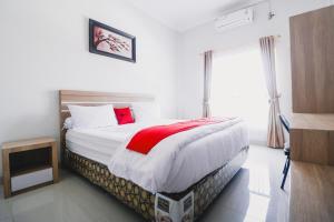 um quarto com uma cama grande e uma janela em RedDoorz near Hermes Place Polonia Medan em Medan