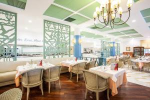 a restaurant with tables and chairs and a chandelier at Grupotel Playa Club in Son Xoriguer +35 photos