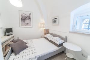 a small white bedroom with a bed and a desk at Casa Pistacchio in Minervino Murge