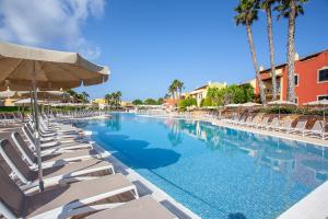 a swimming pool with lounge chairs and umbrellas at Grupotel Playa Club in Son Xoriguer