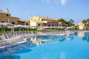 a swimming pool with lounge chairs and umbrellas at Grupotel Playa Club in Son Xoriguer