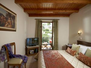 - une chambre avec un lit, une télévision et une chaise dans l'établissement Palazzo Vecchio Exclusive Residence, à Réthymnon