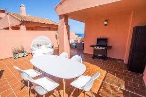 Un patio con mesa y sillas y una estufa. en Los Hidalgos Penthouse, en Manilva
